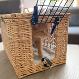 Wicker wood transport basket with metal grid and leather fastenings, cat visible inside the basket.