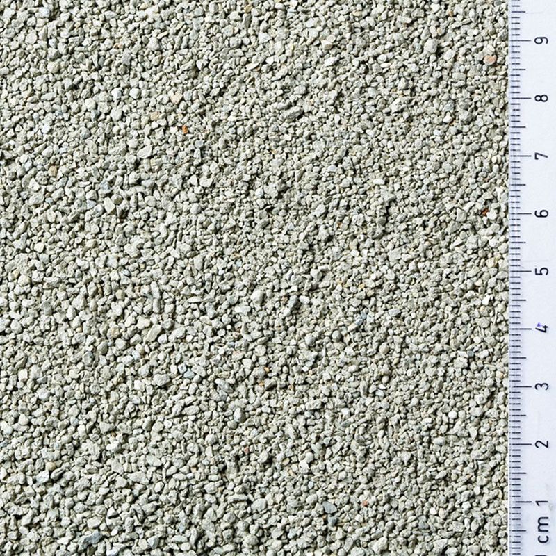 Close-up of light grey granules with a ruler showing particle size from 1 to 9 centimetres for scale.
