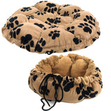 Image shows a round, beige mat with black paw prints that can be used flat or drawn up into a soft nest shape using drawstrings.