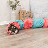 Toy tunnel in red and blue, suitable for small pets. Rabbit sitting in the tunnel on a wooden floor.
