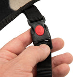 Close-up of a black click fastener with red push button, held by a hand. The fastener is attached to a black strap.