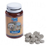 Bottle labelled Biotin Plus with tablets shown beside it, indicating a supplement for skin and hair. Label includes images of a dog and a cat.