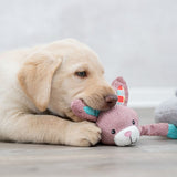 Pink soft toy in the shape of a rabbit with colourful ears and a white face, lying on a wooden floor.