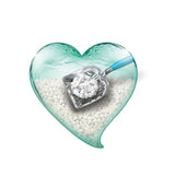 Metal scoop with blue handle lifts white cat litter from a heart-shaped container.