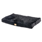 Black rectangular cushion with soft plush surface and a small brown label on the side.