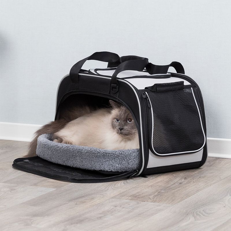 Transport bag with grey inner padding, mesh window and carrying handles. Cat lying relaxed inside the bag.