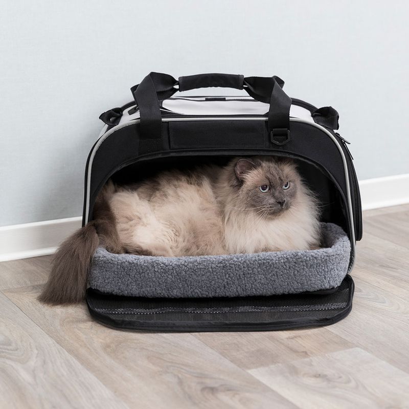 Transport bag with soft grey inner padding, open, with a cat lying inside. Black carrying handles and zip visible.