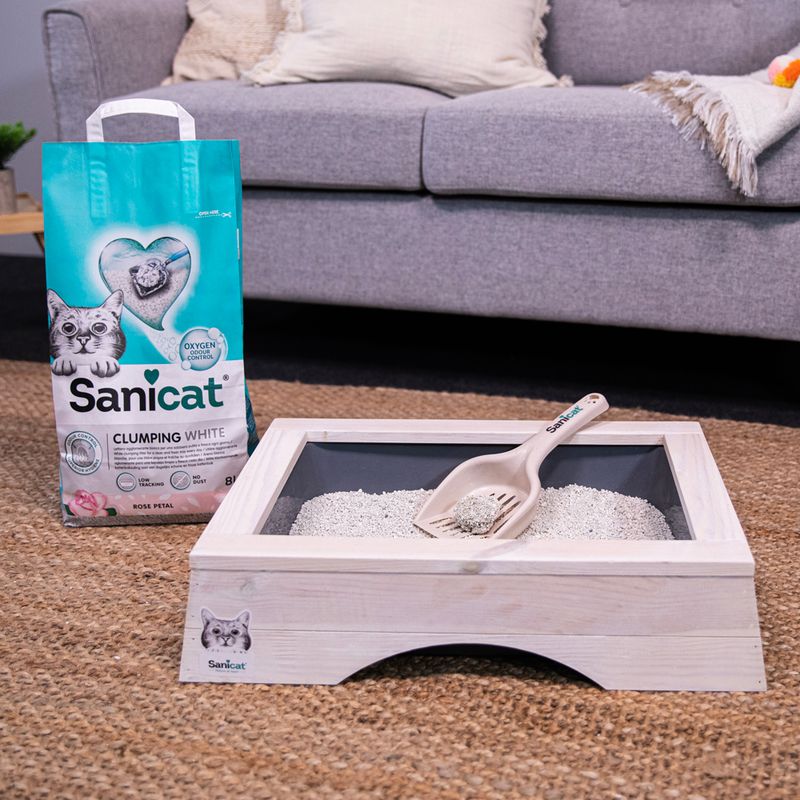 Sanicat Clumping White cat litter with oxygen control, Rose Petal scent. Shown: litter scoop and wooden cat toilet with litter.
