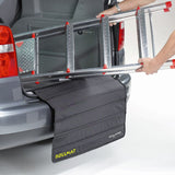 Protective mat placed over a car bumper while a person loads a metal ladder into the boot, showing how the mat prevents scratches during loading.