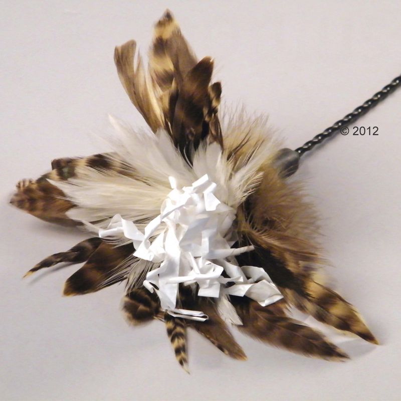 Toy with brown and white feathers and white paper strips, attached to a black chain.