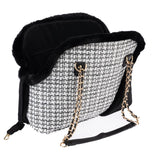 Transport bag with black and white pattern, gold chains as carrying handle and black faux fur trim. Inner compartment visible.