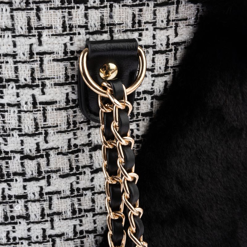 Close-up of a gold chain and black leather strap attached to a textured fabric with a metal ring, showing product material and fastening detail.