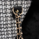 Close-up of a gold chain and black leather strap attached to a textured fabric with a metal ring, showing product material and fastening detail.
