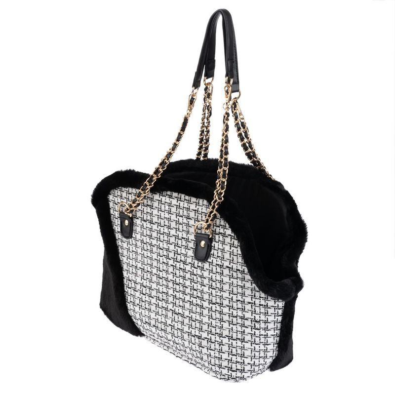 Pet carrier bag with black and white patterned sides, gold chain handles, and black faux fur trim, shown from a side angle.