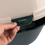 Hand showing the locking mechanism of a green clip on a beige-green cover, presumably for secure lid attachment.