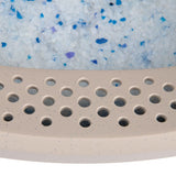 Close-up of cat litter with blue and white crystals and a beige perforated plastic tray.