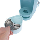 A hand removes a removable stainless steel bowl from a turquoise food dispenser with a rotary mechanism.