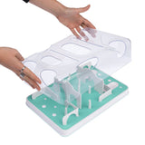 Pet toy with transparent lid removed by hands. Underneath, green base with obstacles and openings.
