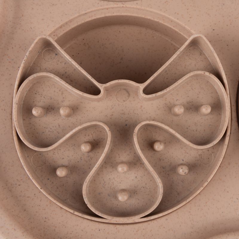 Close-up of a beige anti-gulping bowl with multiple indentations and elevations for slow food intake.