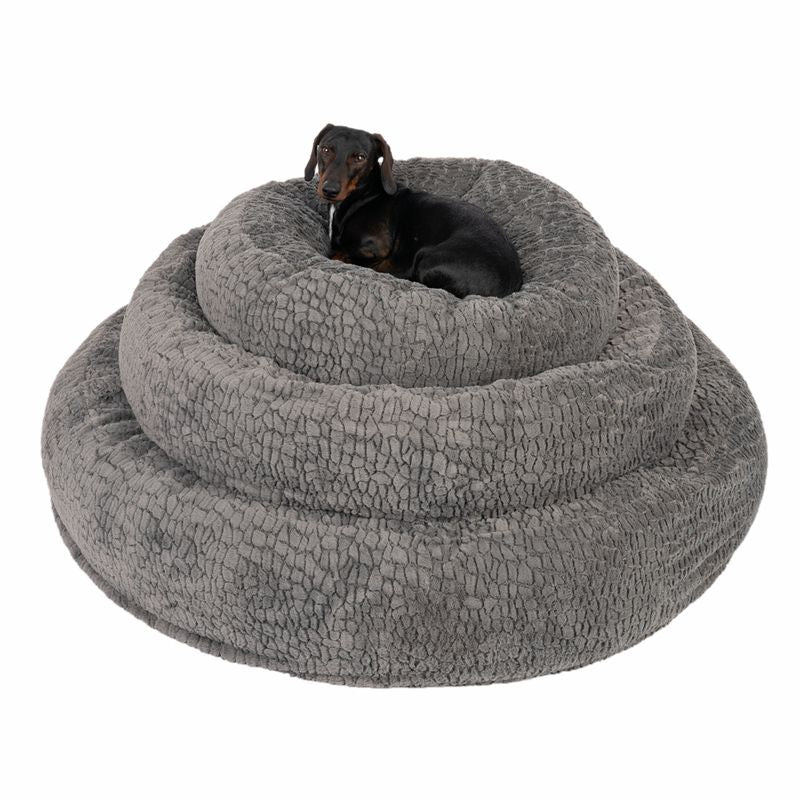 Grey, round dog bed with soft texture. A small dog is lying in it and resting.