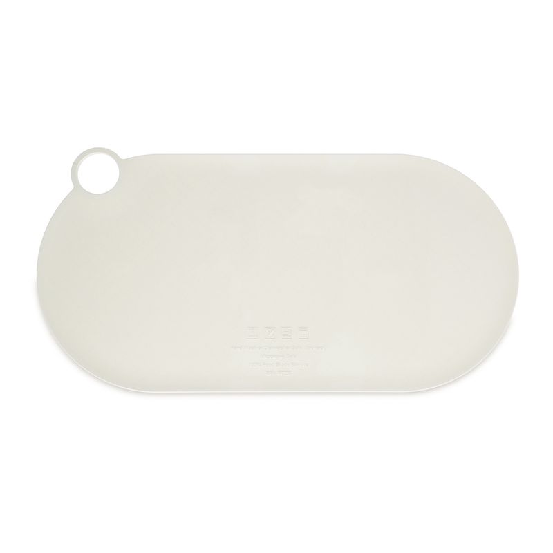 Oval, cream-coloured silicone mat with hole for hanging, suitable as a non-slip base for food bowls.