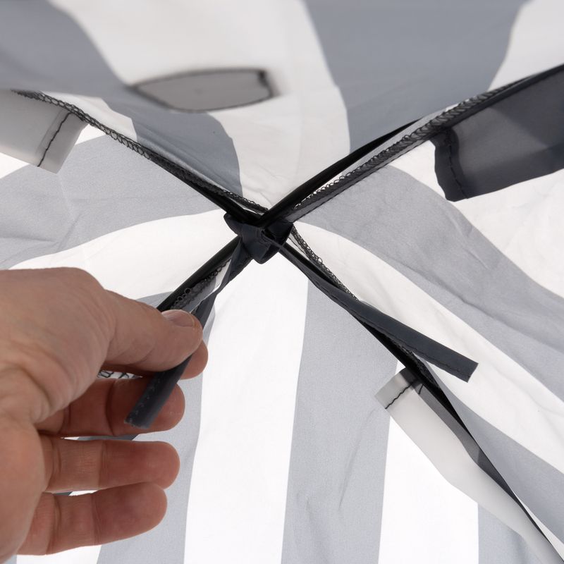 Hand showing the attachment of grey and white fabric material with a black knot.