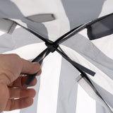 Hand showing the attachment of grey and white fabric material with a black knot.