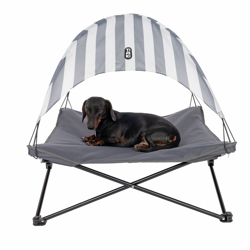Dog lounger with grey fabric and striped sun canopy, brand TIAKI. Suitable for pets to relax in the shade.