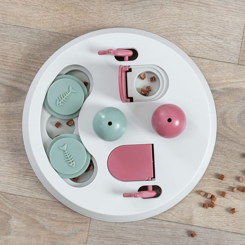 Round interactive toy with compartments, levers and sliding lids in pink and green. Contains small treat pieces as a reward.