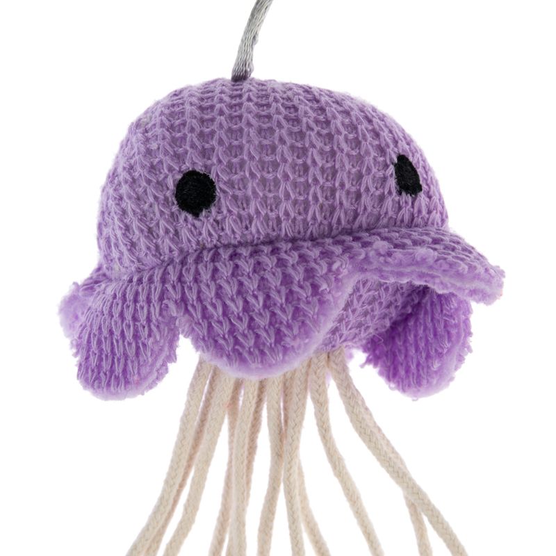 Purple fabric toy in the shape of a jellyfish with a crocheted head and black eyes, plus white cotton threads as tentacles.