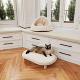 Two cats on modern white furniture: one in a cosy cave bed, the other on a padded lounger. Both pieces with soft padding.