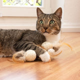 Brown and white cat playing with a rope and feather toy on a wooden floor.