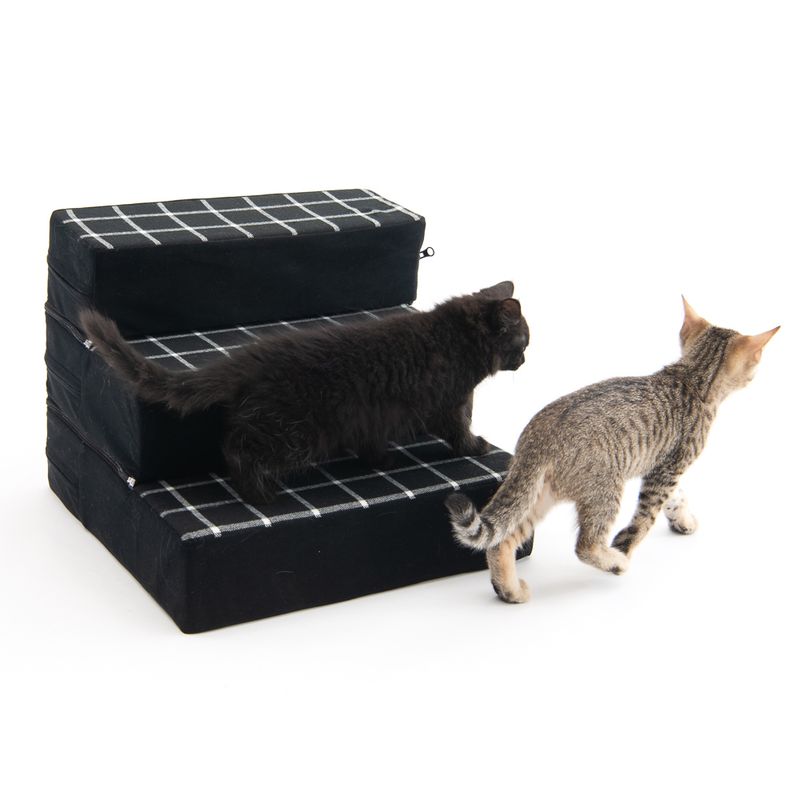Two cats using a three-step black and white checkered pet staircase, demonstrating its function for helping pets reach higher surfaces.