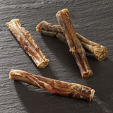 Four dried chew sticks made from natural meat on a dark surface, suitable as a snack for pets.