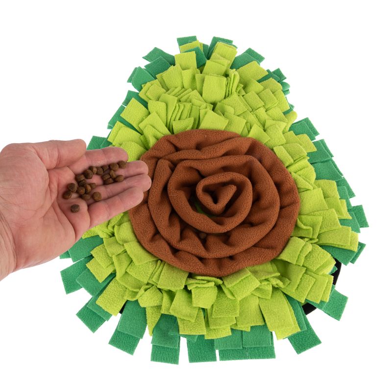 Snuffle mat in green and brown with a hand sprinkling dry food on it.