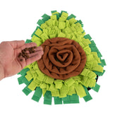 Snuffle mat in green and brown with a hand sprinkling dry food on it.