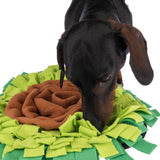 Dog sniffs a green and brown fabric snuffle mat, suitable for search games and activity.