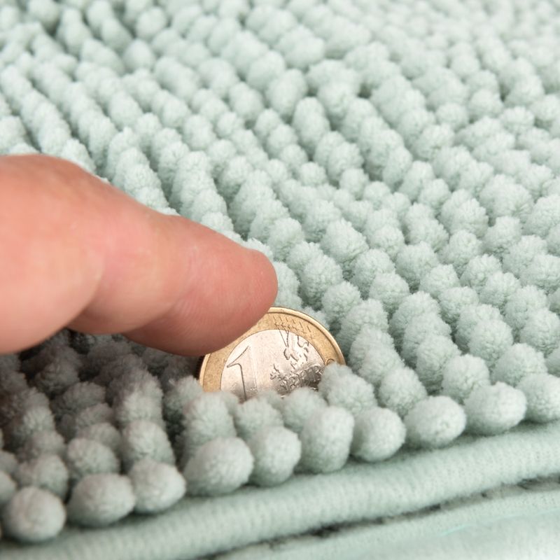 Close-up of a light green textured mat with a finger and a 1-euro coin to show material thickness.