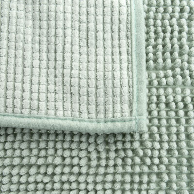 Close-up of a light green mat with two different textures: ribbed surface and soft nubs.