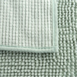 Close-up of a light green mat with two different textures: ribbed surface and soft nubs.