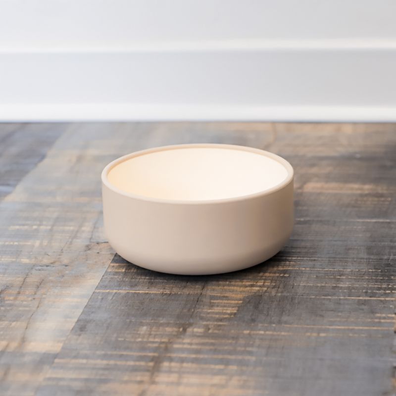 Beige ceramic food bowl on wooden surface, suitable for pet food or water.