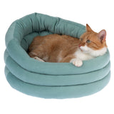 Red and white cat lying in a turquoise, padded pet bed with round design.