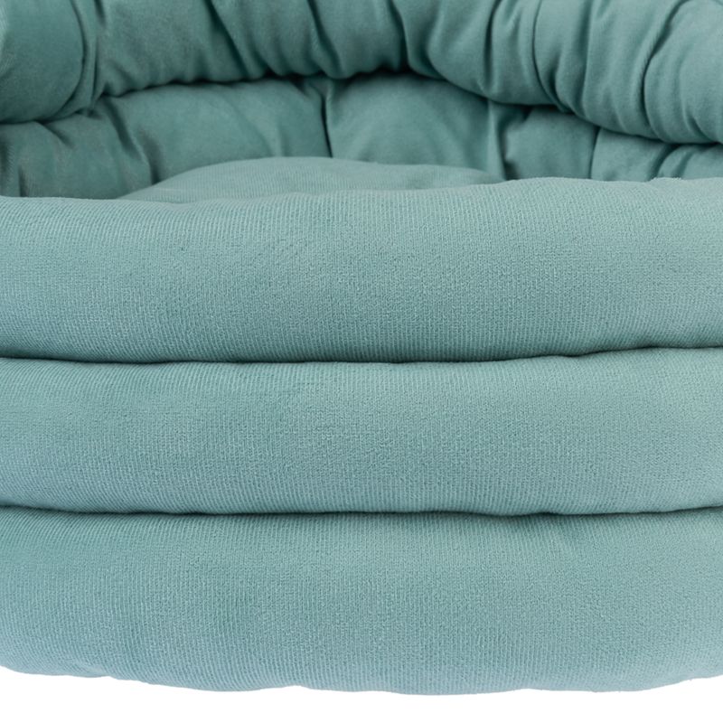 Close-up of a padded, turquoise pet bed with a soft fabric cover.