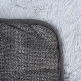 Close-up of a grey, textured mat with rounded edges on a fluffy white background.