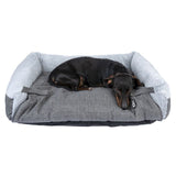 Black dog lying on a grey dog bed with a soft, light grey edge and visible TIAKI logo.