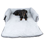 Dog lying on a grey, padded dog bed with fold-out lying surface and raised side edges.