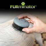 Hand using a round grooming brush with short bristles on wet animal fur, demonstrating how to use the product for washing or brushing.