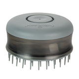 Round grooming brush with soft bristles and a push button on top, designed for detangling and massaging fur during pet care routines.