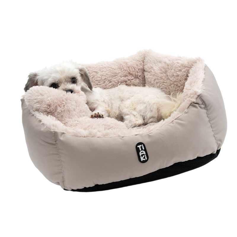 Tiaki dog bed in beige with soft plush lining, small white dog lying inside.