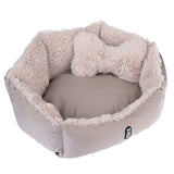 Round, beige pet bed with soft plush edge and matching bone-shaped cushion. 'Tia' brand logo visible on the outside.